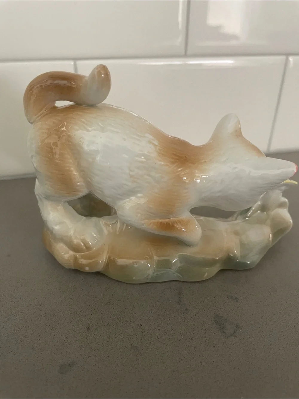 Vintage porcelain cat figurine playing with a butterfly.